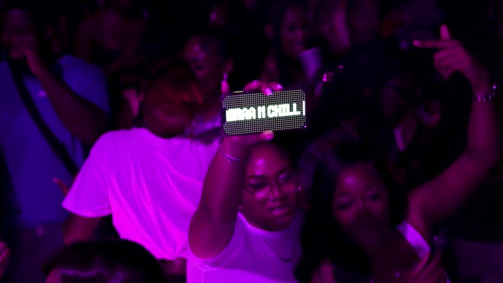 friends holding a nairaa & chill sign above the crowd